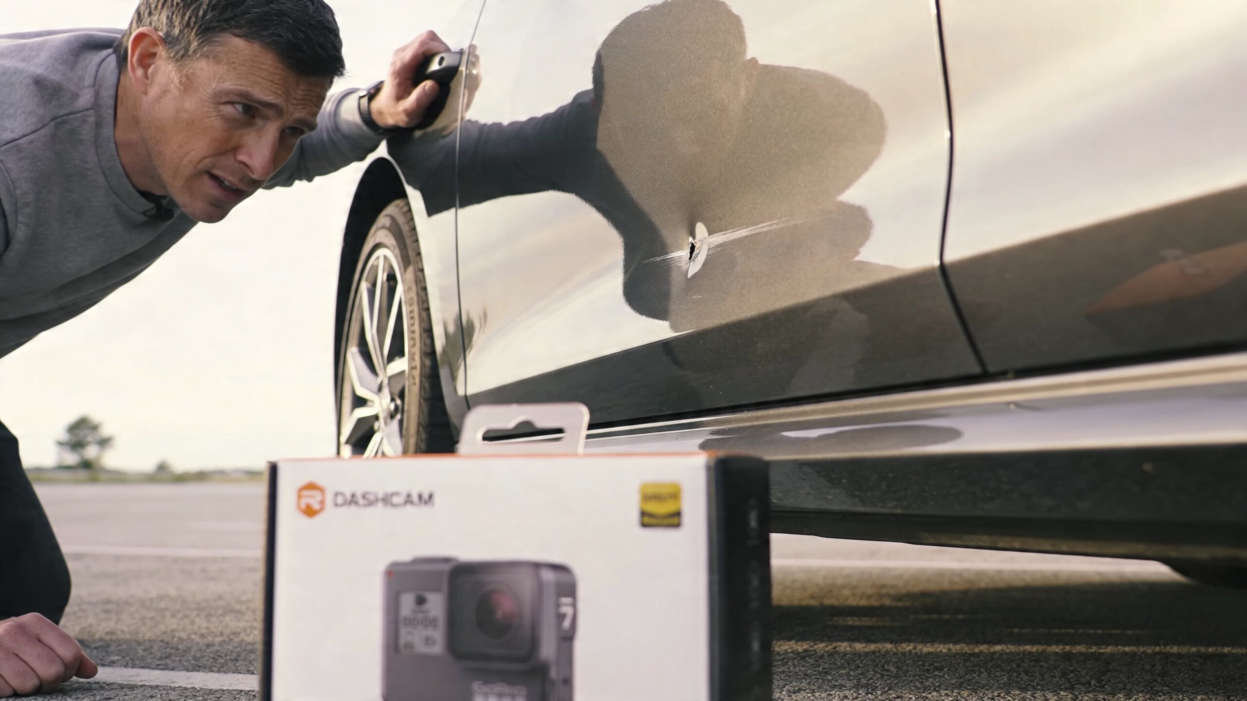 Auto Camera Installation: A Pro's DIY How-To Guide 1 A man examines a deep puncture mark and scratch on the side of a grey car.