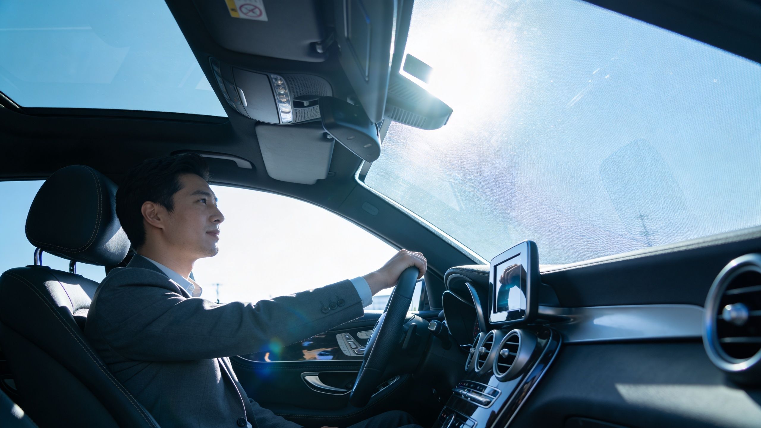 Auto Window Tinting Services: A Whitby Driver's Guide 2 A professional man driving a car with tinted windows in bright sunlight during the day