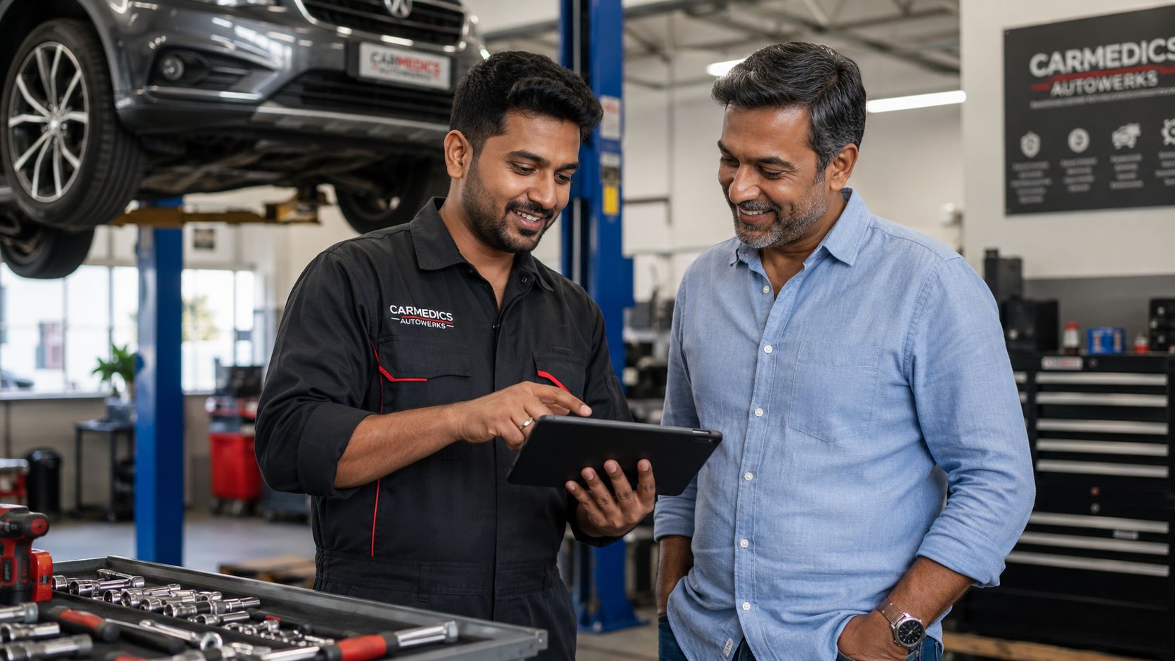 A car mechanic explaining vehicle service details to a customer using a tablet in an auto repair shop.