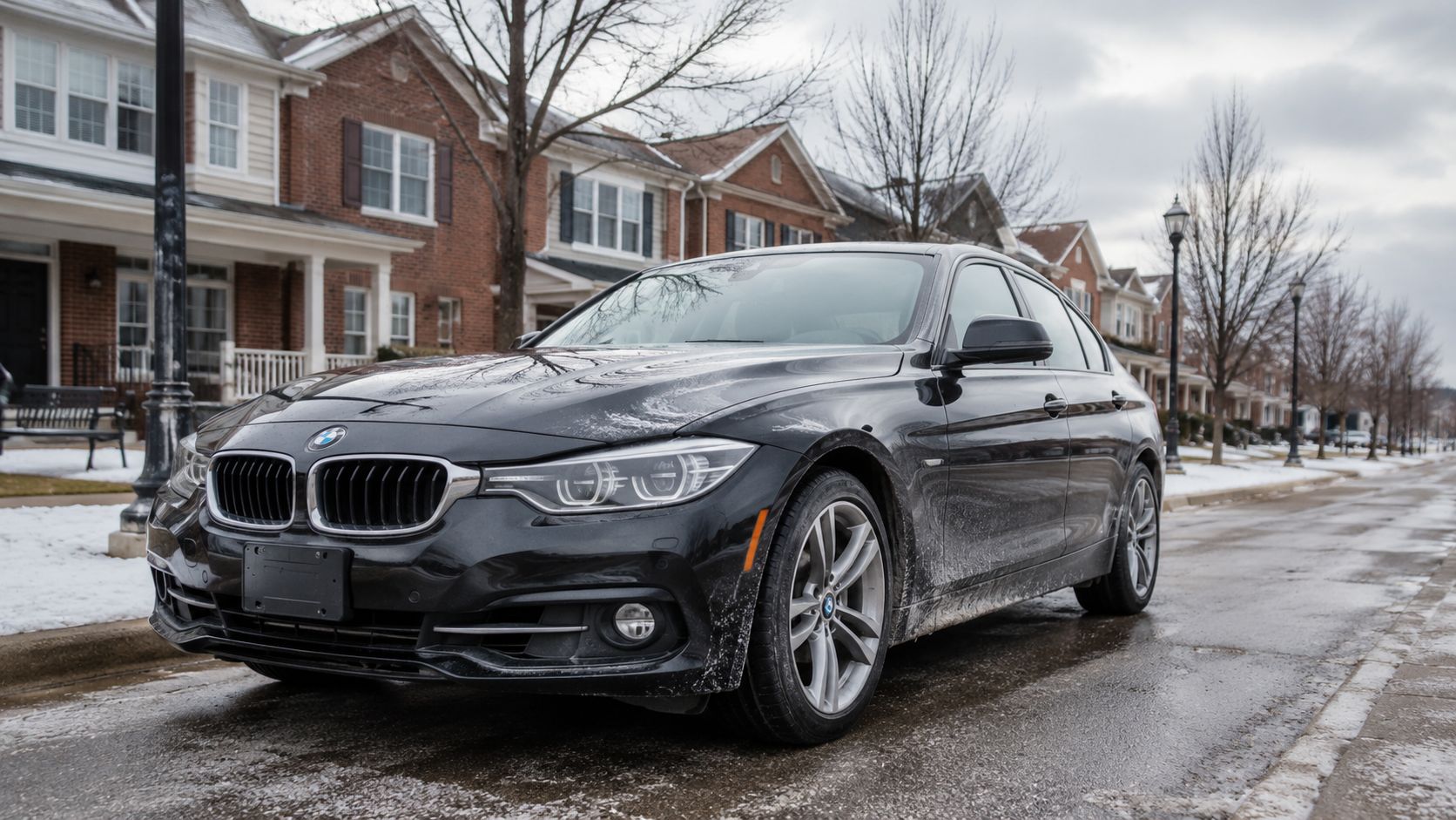 A black BMW parked on a snowy suburban street, reflecting the need for a professional car wash.