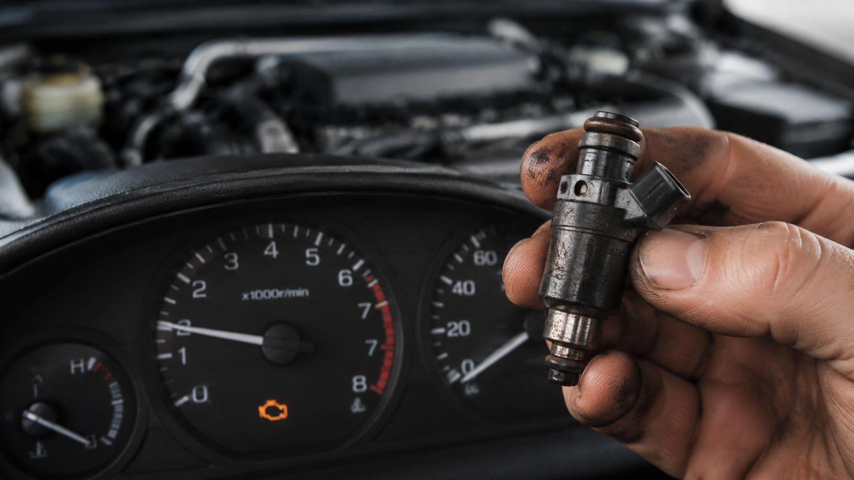 Fuel Injection Cleaning Service Cost: A 2026 Guide 1 A close up view of a person holding a dirty automotive fuel injector in front of car gauges